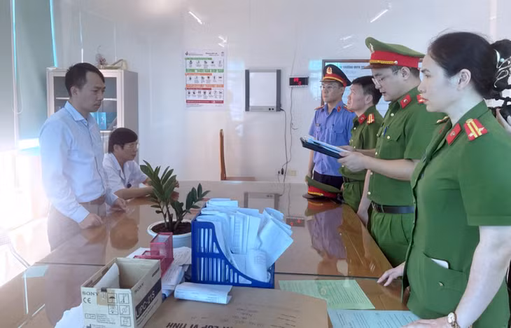 Cảnh sát đọc lệnh bắt với bác sĩ Lượng (góc trái, đứng) tại cơ quan điều tra