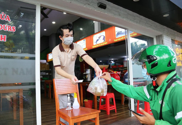 Nhân viên quán phở giao hàng cho shipper trong ngày đầu tiên TP.HCM cho phép quán ăn bán hàng mang đi