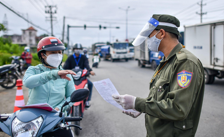 Chị Lan xuất trình giấy tờ khi qua chốt kiểm soát tại quốc lộ 13, đoạn giáp ranh giữa TP Thủ Dầu Một và thị xã Thuận An (Bình Dương). &quot;Tôi có nghe thành phố thông báo điều kiện để di chuyển liên phường. Tôi đã tiêm 2 mũi vaccine và cũng có phiếu xác nhận âm tính&quot;, người phụ nữ nói.