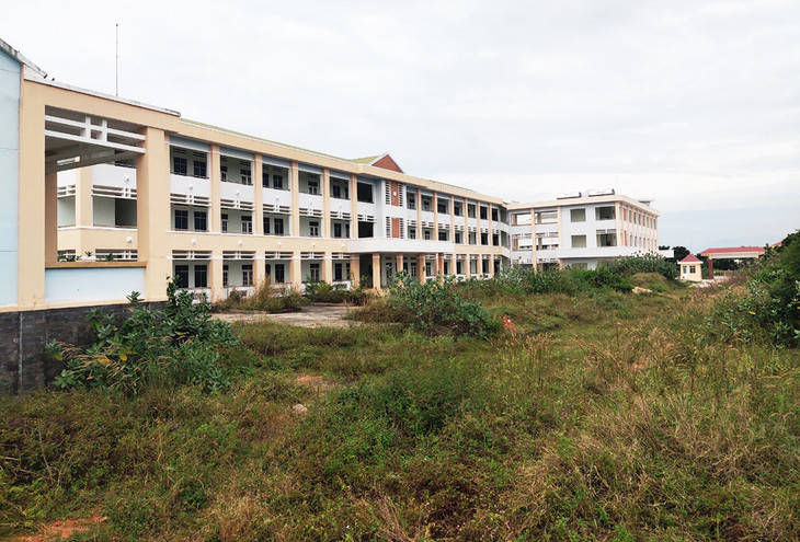 Một dãy nhà của trường nghề phía trước sân cỏ mọc đầy