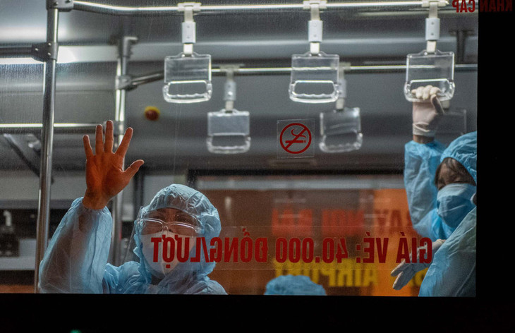 Một số người được chở đi cách ly vẫy tay chào tạm biệt.