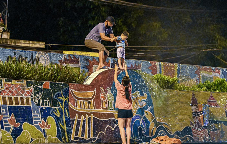 Một người đàn ông gọi điện cho người phía bên trong khu phong tỏa hẹn trước địa điểm sau đó trèo lên mặt đê, bế một em nhỏ trèo rào ra ngoài.