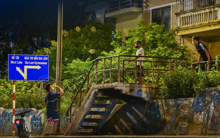 Một số người khác bất chấp lệnh cấm trèo, vẫn cố lên mặt đê để nhận hàng của người ở ngoài khu vực phong tỏa ném vào trong.