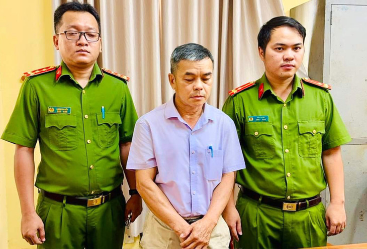 Ông Phạm Xuân Lộc (giữa) khi cảnh sát tống đạt quyết định bắt tạm giam