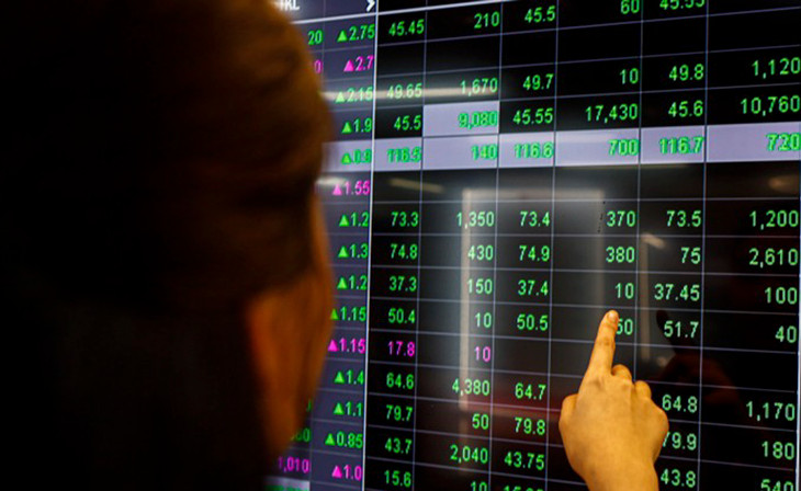 Nhà đầu tư đang theo dõi bảng điện tại một công ty chứng khoán Nhà đầu tư đang theo dõi bảng điện tại một công ty chứng khoán