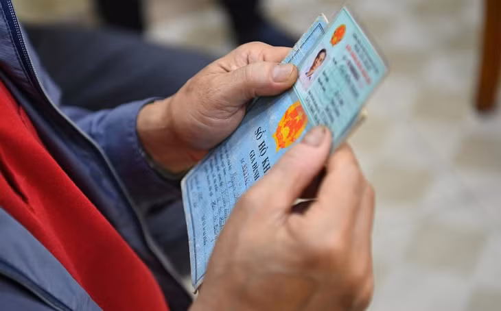 Một người dân cầm chứng minh thư và hộ khẩu giấy đi làm thẻ căn cước công dân gắn chip