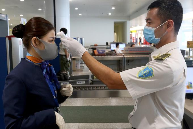 Nhân viên an ninh hàng không kiểm tra thân nhiệt cho tiếp viên Nhân viên an ninh hàng không kiểm tra thân nhiệt cho tiếp viên