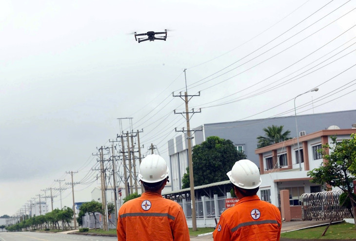 Nhân viên Công ty Điện lực Bình Dương ứng dụng thiết bị flycam kiểm tra lưới điện. Ảnh: Huy Hùng - TTXVN