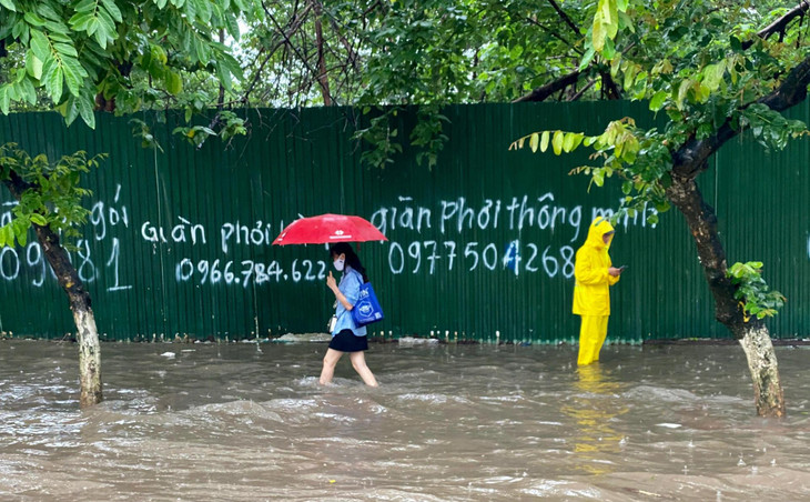 Người đi bộ không còn cách nào khác phải đánh liều đi dò chân từng bước trên vỉa hè. Công nhân thoát nước cũng đã có mặt, đứng chặn và cảnh báo người dân tránh đi qua các điểm có hố sâu hoặc cống thoát nước đang mở nắp
