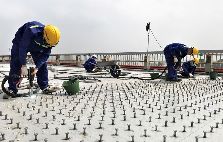 Công nhân tiến hành hàn đinh neo để tạo liên kết giữa bản mặt thép hiện tại và bê tông siêu tính năng UHPC nhằm tăng cường kết cấu chịu lực của mặt cầu Thăng Long