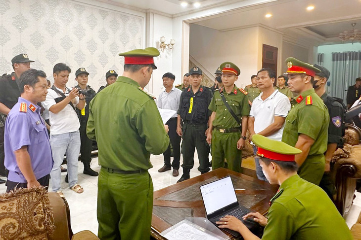 Cảnh sát đọc lệnh bắt tạm giam, khám xét nhà riêng của Trần Văn Thuận (áo thun trắng, phải)