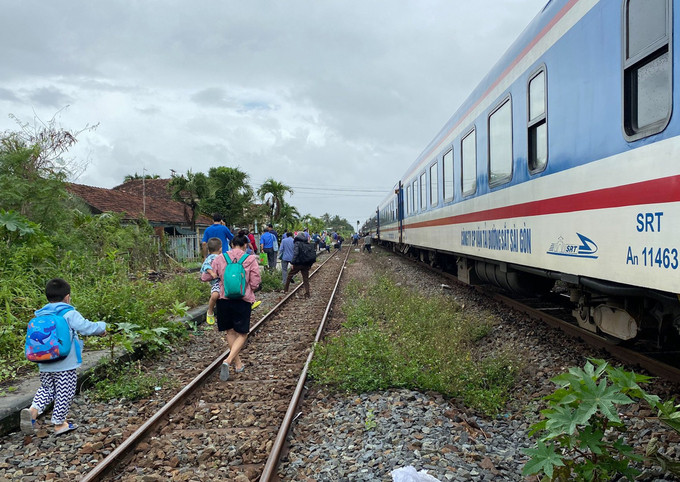 Hành khách xuống tàu để đi đường bộ qua vùng nước ngập khu vực Nha Trang (Khánh Hòa)