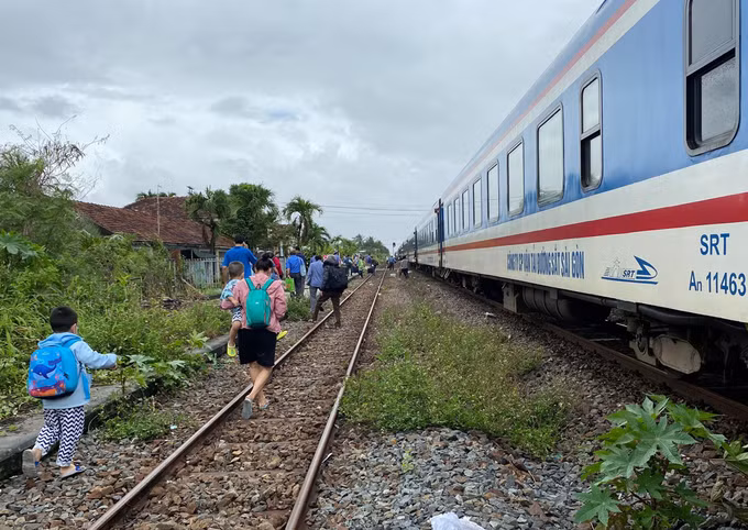 Hành khách xuống tàu để đi đường bộ qua vùng nước ngập khu vực Nha Trang (Khánh Hòa)