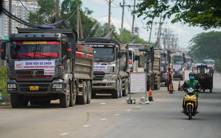 Bên ngoài dự án, hàng chục xe chở cát, đá, xếp hàng dài trên đại lộ Nguyễn Văn Linh, huyện Bình Chánh (TP.HCM). Theo đại diện nhà thầu chính, đội xe tải chở cát, đá được huy động khoảng 120 đầu xe/ngày, chạy liên tục 3 ca, thêm 4 đường ống bơm cát từ sông vào. Dự kiến lượng cát cho công trình này trong 1 ngày phải đạt được 14.000 m3.