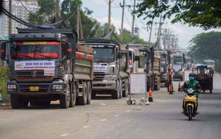Bên ngoài dự án, hàng chục xe chở cát, đá, xếp hàng dài trên đại lộ Nguyễn Văn Linh, huyện Bình Chánh (TP.HCM). Theo đại diện nhà thầu chính, đội xe tải chở cát, đá được huy động khoảng 120 đầu xe/ngày, chạy liên tục 3 ca, thêm 4 đường ống bơm cát từ sông vào. Dự kiến lượng cát cho công trình này trong 1 ngày phải đạt được 14.000 m3.