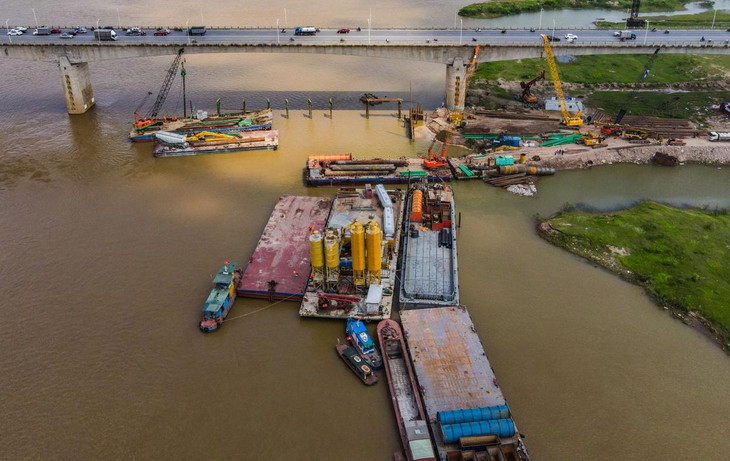 Nhà thầu dùng nhiều xà lan làm đường nổi, huy động máy xúc, cần cẩu ra khoan đào ở lòng sông sau đó đóng cọc xung quanh phạm vi đổ trụ. Một trạm trộn bê tông nổi được lắp đặt ngay giữa sông Hồng.