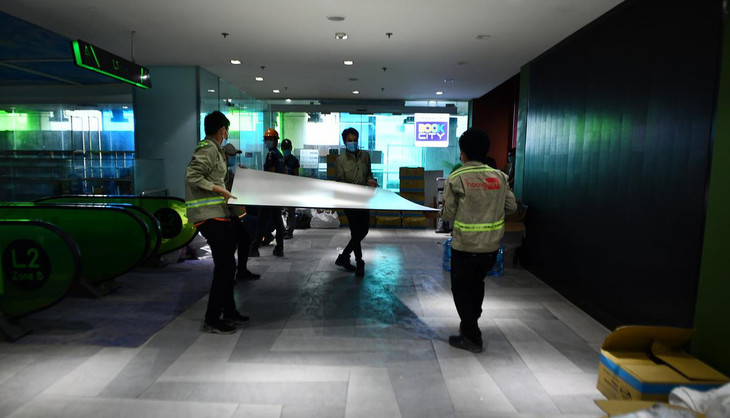 Phía dưới khu căn hộ, công nhân đang gấp rút cải tạo khu trung tâm thương mại thành bệnh viện dã chiến.