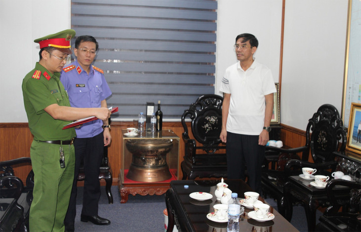 Ông Doãn Tiến Dũng, Chủ tịch UBND thị xã Cửa Lò (góc phải) nghe cảnh sát đọc lệnh bắt