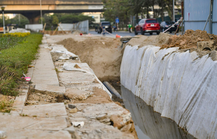 Nhiều hố sâu được rào chắn tạm bợ tại vườn hoa nút giao Vành đai 3. Nhà thầu thi công liên tục, kể cả trong khung giờ cao điểm. Sở GTVT Hà Nội cho biết thời gian thi công kéo dài đến hết tháng 1/2022.