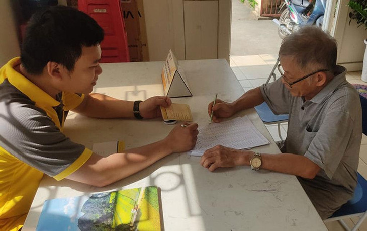 Nhân viên bưu điện hướng dẫn chi trả trợ cấp cho người già trên 80 tuổi