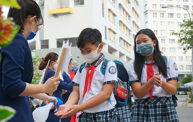 Học sinh trường Tiểu học Lê Đức Thọ, quận Gò Vấp được giáo viên đón trước cổng, giúp rửa tay, đo thân nhiệt trước khi vào lớp. Ảnh minh họa