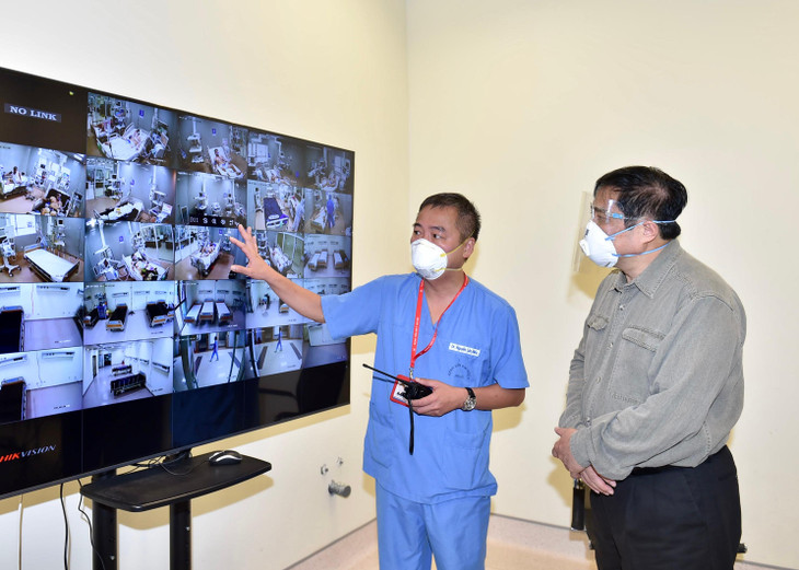 Bác sĩ Nguyễn Lân Hiếu, Giám đốc Bệnh viện Đại học Y Hà Nội phụ trách Bệnh viện dã chiến điều trị COVID-19 tại Bệnh viện quốc tế Becamex giới thiệu với Thủ tướng hoạt động điều trị chung của Bệnh viện dã chiến qua hệ thống giám sát trung tâm. Ảnh: VGP