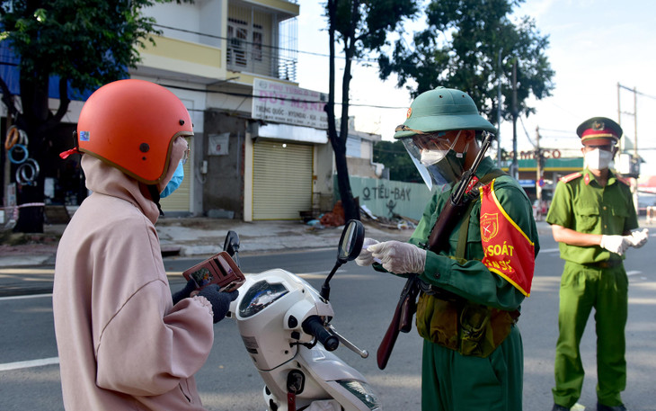 Binh nhất Đào Thanh Điền ở đơn vị Sư Đoàn Bộ binh 5 kiểm tra giấy tờ lưu thông của người dân khi ra đường tại chốt kiểm tra trên đường Đinh Bộ Lĩnh, Quận Bình Thạnh. &quot;Đơn vị chúng tôi từ Tây Ninh đến TP.HCM từ hôm qua, mọi người được phân về các chốt để hỗ trợ làm việc&quot;, Binh nhất Điền cho biết