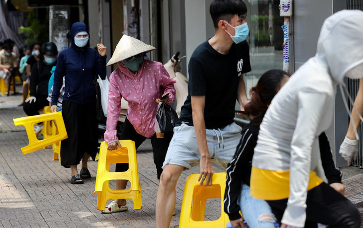 Người dân xếp hàng ngồi chờ đến lượt mua thức ăn tại một cửa hàng thực phẩm trên đường Nguyễn Thiện Thuật (Quận 3, TP.HCM).