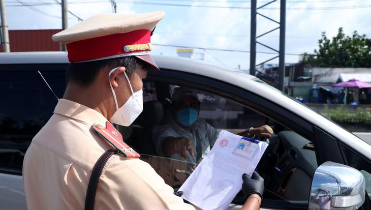 Người dân xuất trình giấy đi đường khi lưu thông qua chốt kiểm soát dịch.