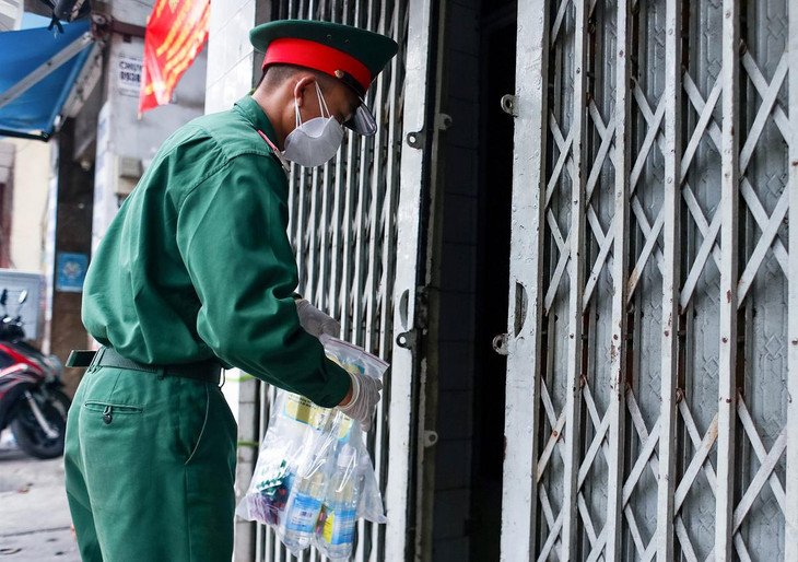 Một chiến sĩ trao thuốc cho một gia đình có 6 ca F0 đang tự điều trị tại nhà trên đường An Dương Vương (Quận 5)