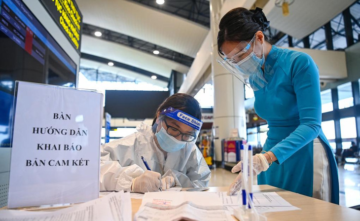 Tiếp viên hành không hướng dẫn hành khách khai báo y tế tại sân bay Nội Bài