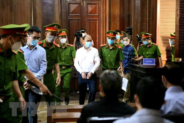 Bị cáo Lê Tấn Hùng (giữa), nguyên Tổng Giám đốc Tổng Công ty Nông nghiệp Sài Gòn được đưa tới phiên tòa. Ảnh: TTXVN