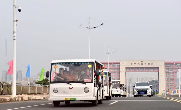 Các xe trung chuyển (xe điện) chở khách du lịch xuất cảnh đi qua vạch phân quảng cầu Bắc Luân 2.