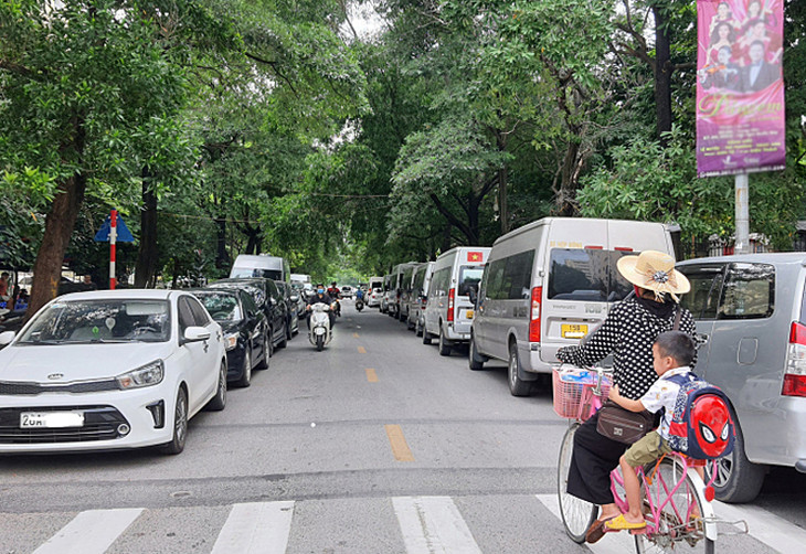 Xe đỗ kín hai bên lề đường tại phố Đinh Núp, quận Cầu Giấy, Hà Nội, khiến diện tích lòng đường bị thu hẹp