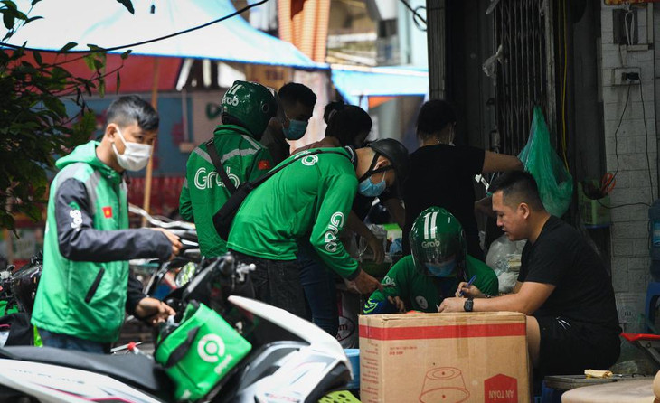 Tại một quán ăn trên đường Vũ Thạnh (Đống Đa, Hà Nội), các shipper chen chúc nhau để lấy đơn, tuy nhiên họ không đảm bảo an toàn về giãn cách phòng dịch. Còn chủ quán cũng không đeo khẩu trang khi làm việc.