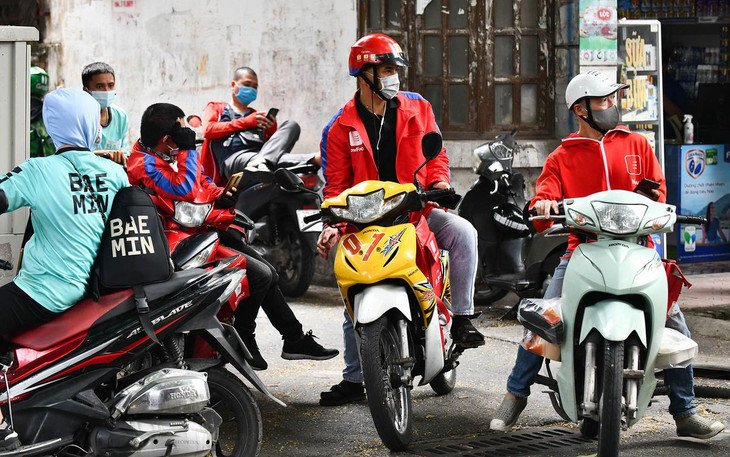 Tại phố Thành Công, nơi có nhiều hàng quán bán đồ ăn, các shipper ngồi chờ trên vỉa hè chờ đến giờ &quot;nổ đơn&quot;.