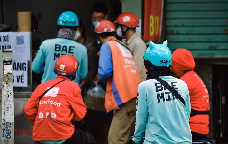 Tại nhiều tiệm bán đồ ăn, shipper chen chúc nhau không đảm bảo giãn cách. Một người giao hàng cho biết theo thông báo mới của công ty, chỉ có 50% tài xế của hãng được hoạt động.