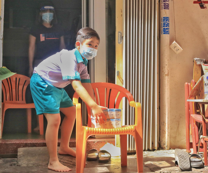 Một em nhỏ nhận sữa tươi do đại diện Hội phụ nữ phường trao.