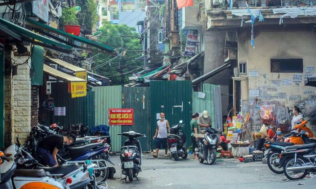 Một chốt cứng được rào bằng tôn chặn lối vào Đê Trần Khát Chân từ đường Nguyễn Khoái. Bên ngoài cảnh sinh hoạt tập nập sau nới lỏng giãn cách.