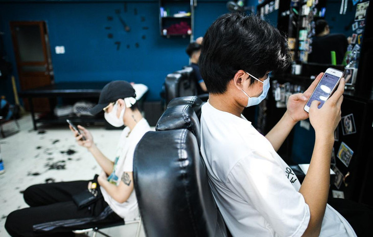 Đã 3 tháng nay, anh Tuấn Anh (ngồi bên phải) chưa được cắt tóc. Sáng nay, anh đã tới tiệm khá sớm, nhưng phải ngồi chờ gần 2 tiếng vẫn chưa đến lượt. "Biết tin được cắt tóc là mừng rồi. Để tóc 3 tháng chưa cắt nên tôi khó chịu lắm. Đợi lâu một chút cũng không sao vì tôi đã đoán trước hôm nay chắc sẽ đông", anh Tuấn Anh chia sẻ. Đã 3 tháng nay, anh Tuấn Anh (ngồi bên phải) chưa được cắt tóc. Sáng nay, anh đã tới tiệm khá sớm, nhưng phải ngồi chờ gần 2 tiếng vẫn chưa đến lượt. "Biết tin được cắt tóc là mừng rồi. Để tóc 3 tháng chưa cắt nên tôi khó chịu lắm. Đợi lâu một chút cũng không sao vì tôi đã đoán trước hôm nay chắc sẽ đông", anh Tuấn Anh chia sẻ.