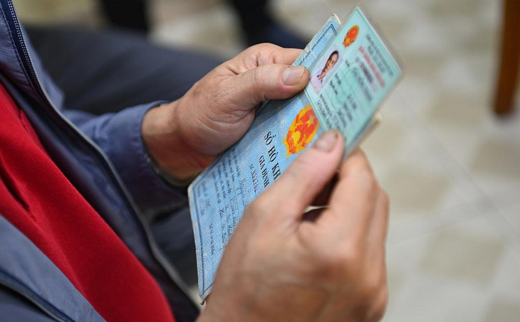 Một người dân cầm chứng minh thư và hộ khẩu giấy đi làm thẻ căn cước công dân gắn chip