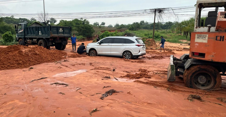 Một ô tô đi qua đường Phú Hài bị mắc kẹt trong bùn cát đỏ