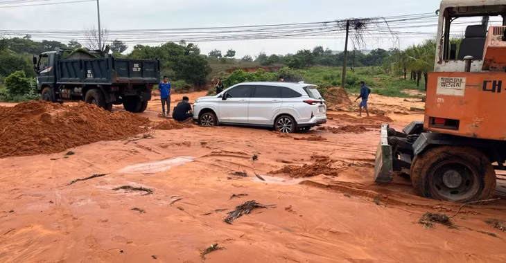 Một ô tô đi qua đường Phú Hài bị mắc kẹt trong bùn cát đỏ
