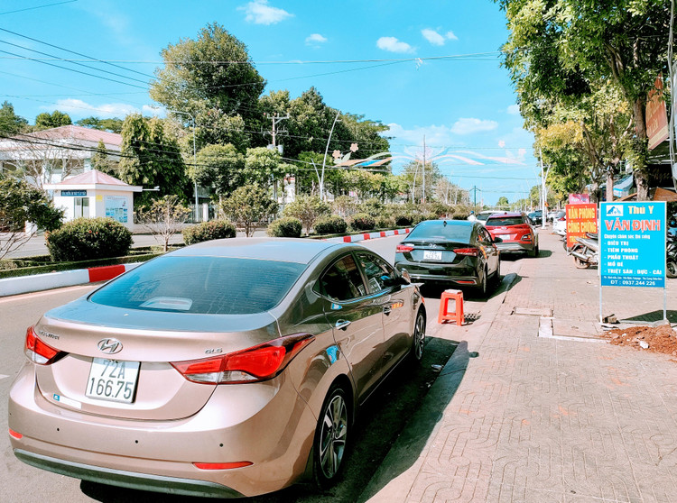 Dọc tuyến đường Hùng Vương - một tuyến đường trung tâm của huyện này - ô tô nối tiếp nhau thành dãy dài trước các văn phòng công chứng. Ảnh: Ngô Bảo Tín