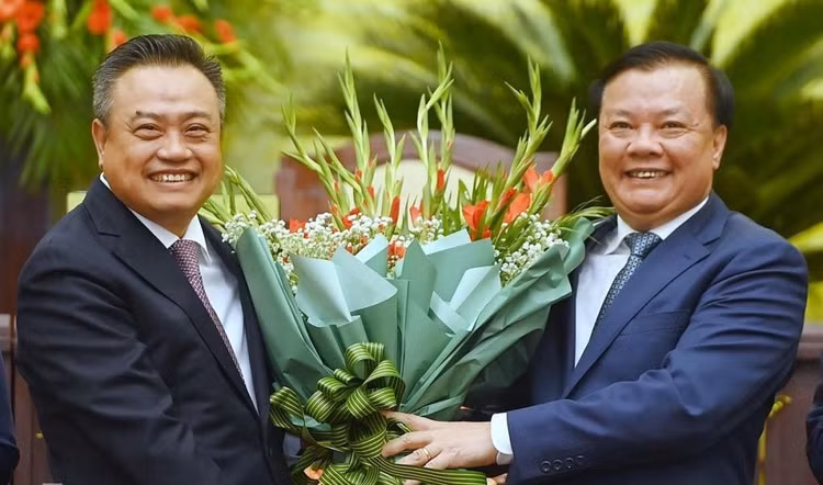 Tân Chủ tịch UBND TP. Hà Nội Trần Sỹ Thanh (trái) nhận hoa chúc mừng từ Bí thư Thành ủy Hà Nội Đinh Tiến Dũng. Ảnh: Giang Huy